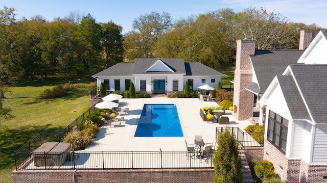 rear view of property featuring a patio, a fenced in pool, and a yard