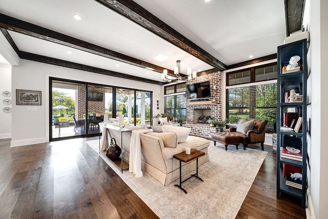 living room with dark wood-type flooring, beamed ceiling, an inviting chandelier, and a brick fireplace