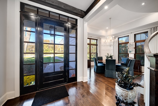 foyer with beam ceiling, a notable chandelier, and wood-type flooring