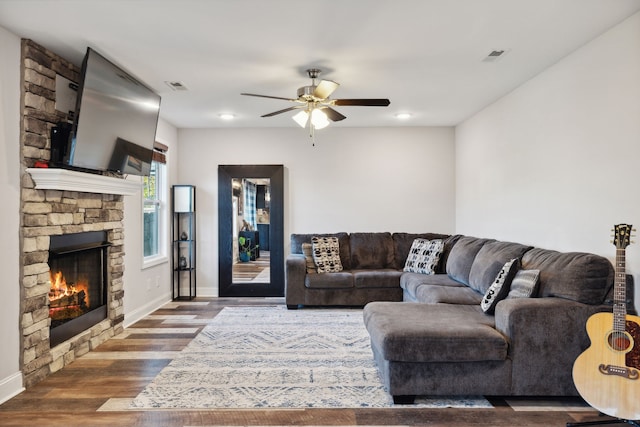 living room featuring dark wood-type flooring, a fireplace, and ceiling fan