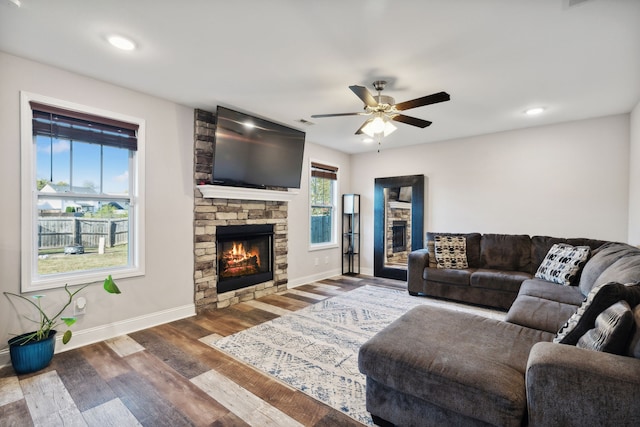 living room featuring hardwood / wood-style flooring, a stone fireplace, and ceiling fan