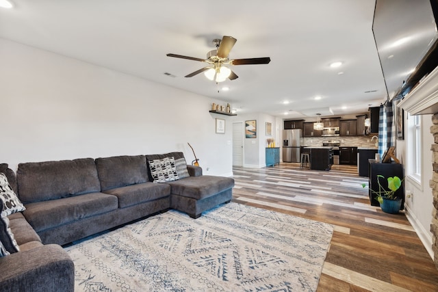 living room featuring sink, hardwood / wood-style flooring, and ceiling fan