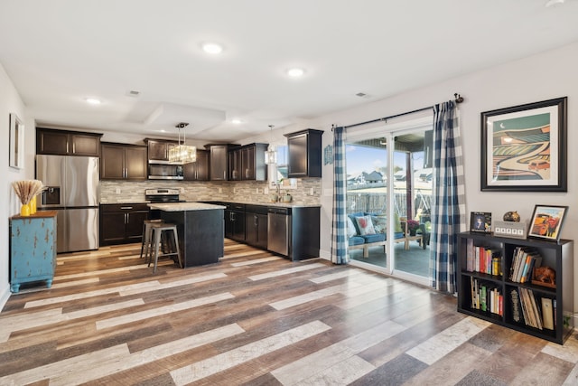 kitchen featuring a kitchen island, appliances with stainless steel finishes, a kitchen breakfast bar, light hardwood / wood-style floors, and decorative light fixtures