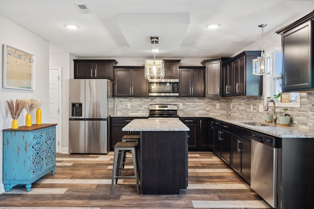 kitchen featuring hanging light fixtures, wood-type flooring, sink, a center island, and appliances with stainless steel finishes