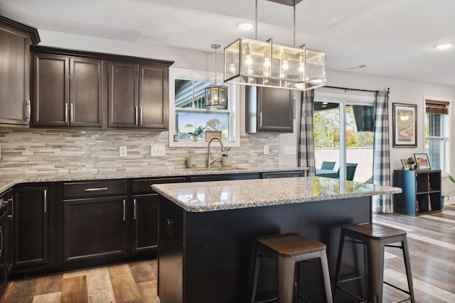 kitchen with a center island, decorative backsplash, light hardwood / wood-style flooring, and pendant lighting