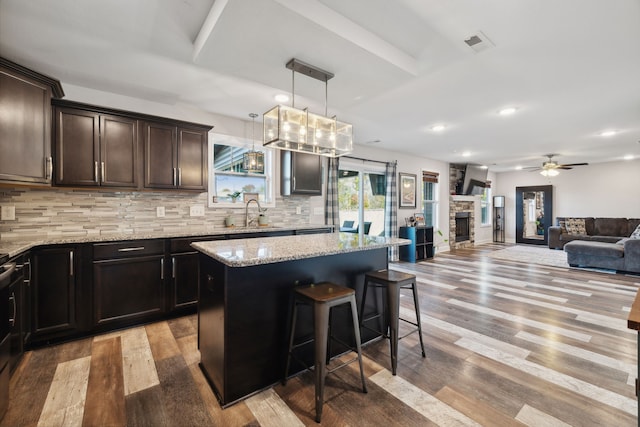 kitchen featuring a fireplace, backsplash, a center island, light hardwood / wood-style floors, and pendant lighting