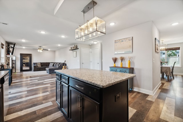 kitchen with dark wood-type flooring, ceiling fan, a center island, and decorative light fixtures