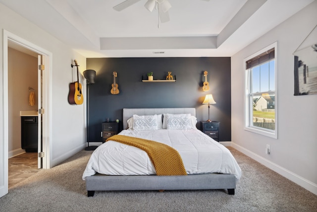 carpeted bedroom featuring ceiling fan and a tray ceiling