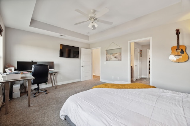 carpeted bedroom with a raised ceiling and ceiling fan