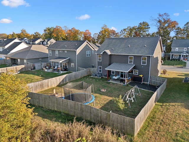 back of property with a trampoline and a lawn