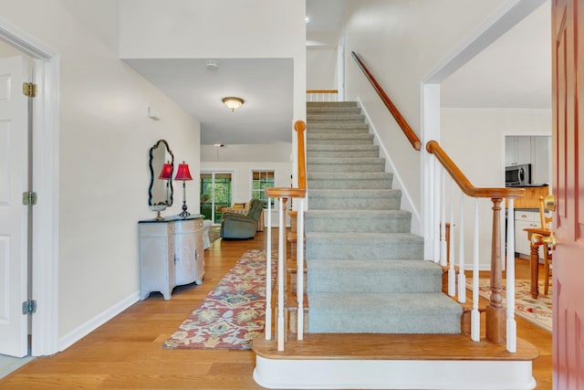 staircase featuring ornamental molding and hardwood / wood-style floors