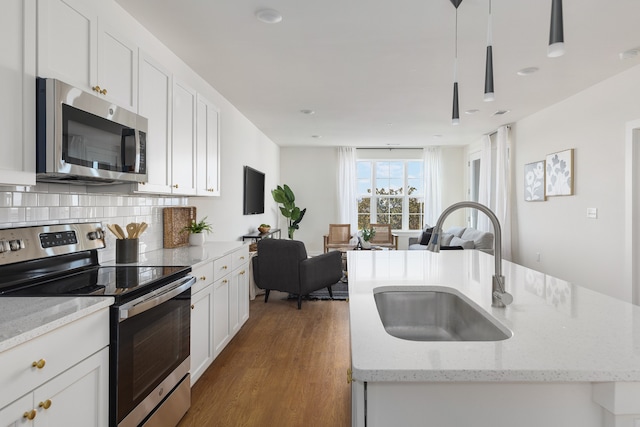 kitchen featuring appliances with stainless steel finishes, sink, an island with sink, pendant lighting, and dark hardwood / wood-style floors