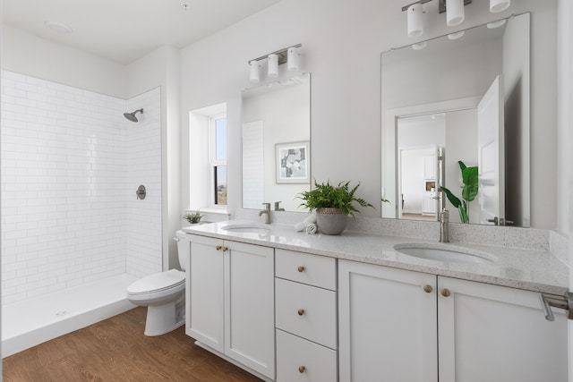 bathroom with vanity, toilet, wood-type flooring, and tiled shower