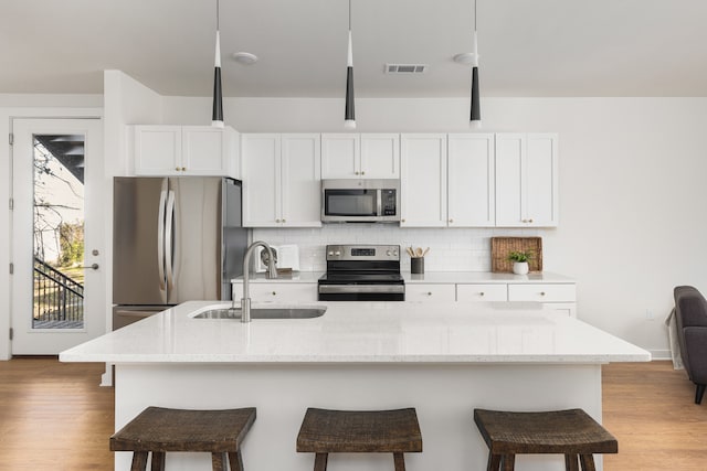 kitchen featuring white cabinets, a kitchen island with sink, stainless steel appliances, and sink