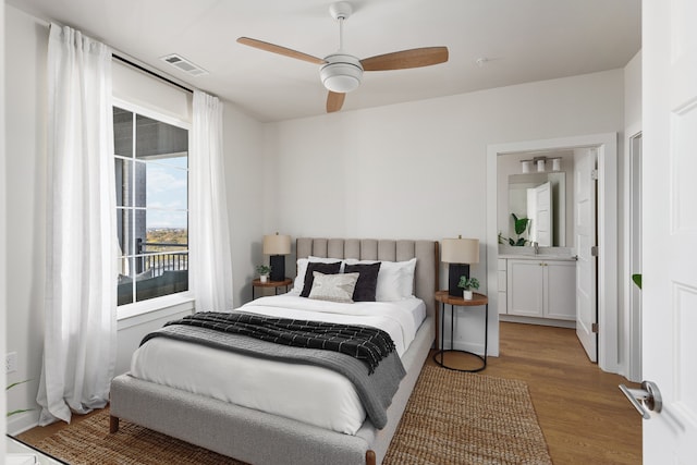 bedroom with connected bathroom, ceiling fan, and light wood-type flooring