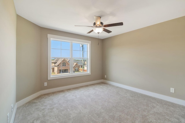 spare room with carpet floors, a ceiling fan, and baseboards