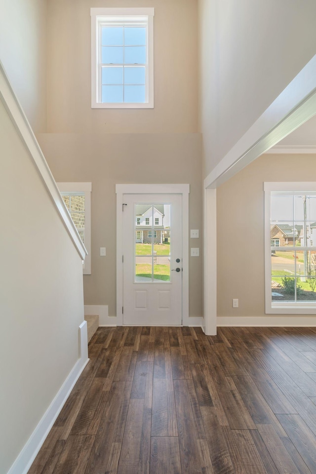foyer featuring hardwood / wood-style floors, a high ceiling, baseboards, and stairway