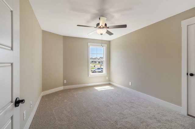 carpeted empty room with ceiling fan and baseboards