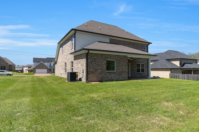 rear view of house featuring a lawn, brick siding, roof with shingles, and central AC