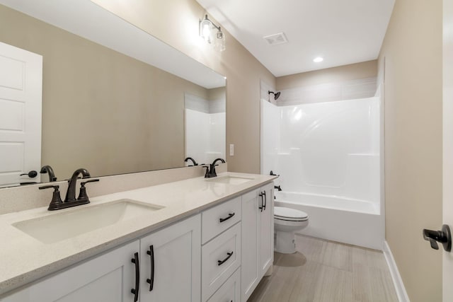 bathroom featuring bathing tub / shower combination, a sink, double vanity, and toilet
