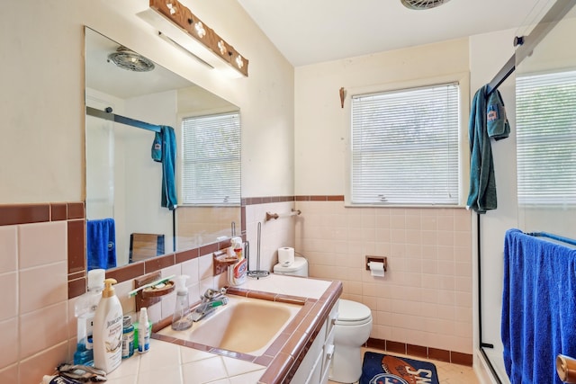 bathroom featuring toilet, tile patterned floors, walk in shower, tile walls, and vanity