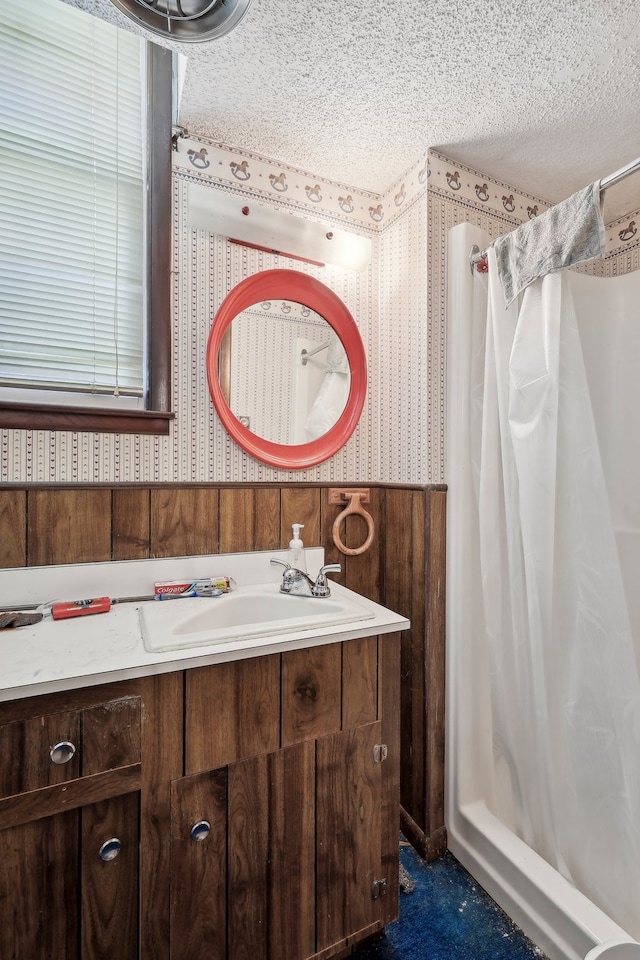 bathroom with vanity, wooden walls, a shower with shower curtain, and a textured ceiling