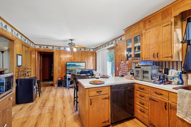 kitchen with black dishwasher, wood walls, kitchen peninsula, light hardwood / wood-style floors, and ceiling fan