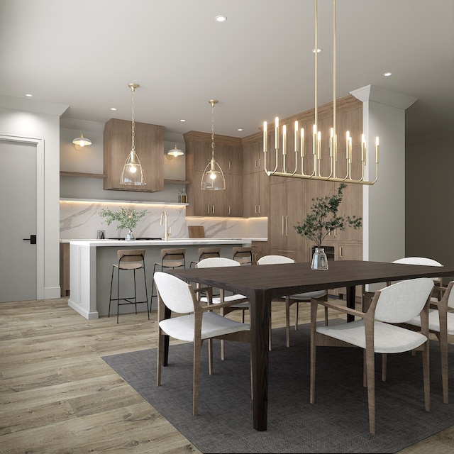 dining space with crown molding, light hardwood / wood-style flooring, and an inviting chandelier