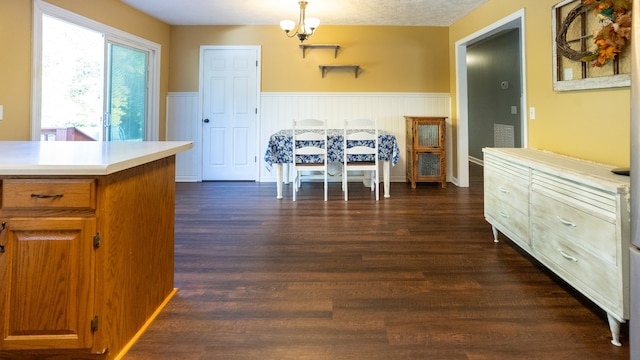 kitchen with a textured ceiling, decorative light fixtures, dark hardwood / wood-style floors, and an inviting chandelier