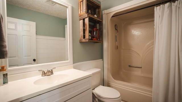 full bathroom with vanity, a textured ceiling, shower / tub combo with curtain, and toilet