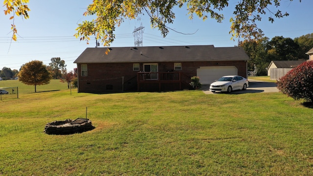 rear view of house featuring an outdoor fire pit, a storage unit, a deck, a lawn, and a garage