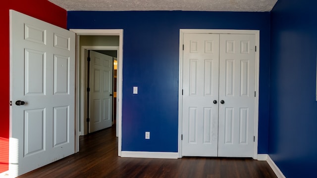 unfurnished bedroom with a textured ceiling, dark hardwood / wood-style floors, and a closet