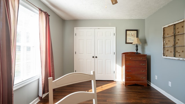 unfurnished bedroom featuring multiple windows, dark hardwood / wood-style floors, a textured ceiling, and ceiling fan