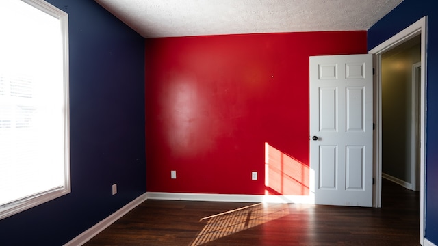 unfurnished room with a textured ceiling, dark hardwood / wood-style floors, and a healthy amount of sunlight