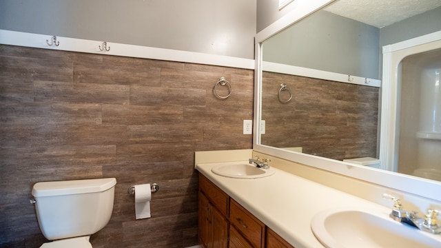 bathroom featuring tile walls, vanity, a textured ceiling, and toilet