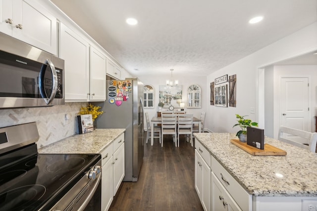 kitchen featuring decorative backsplash, white cabinets, dark hardwood / wood-style flooring, appliances with stainless steel finishes, and pendant lighting