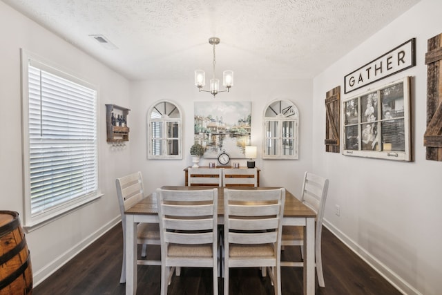 dining area featuring an inviting chandelier, a textured ceiling, and dark hardwood / wood-style flooring