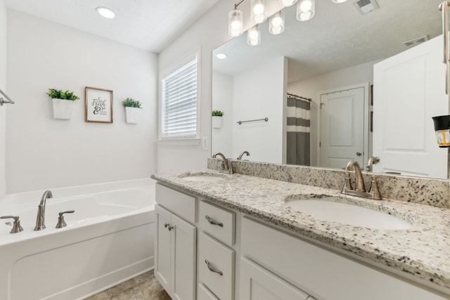 bathroom with a bathing tub, a textured ceiling, and vanity