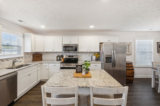 kitchen featuring stainless steel appliances, sink, light stone counters, and dark hardwood / wood-style flooring