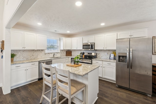 kitchen with appliances with stainless steel finishes, white cabinets, and dark hardwood / wood-style flooring