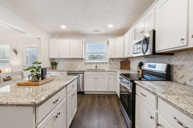 kitchen featuring appliances with stainless steel finishes, white cabinetry, and a healthy amount of sunlight