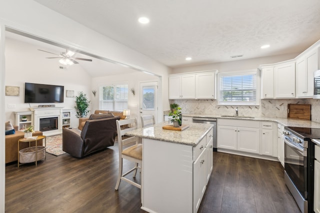 kitchen featuring a kitchen bar, a kitchen island, stainless steel range with electric stovetop, white cabinetry, and dark hardwood / wood-style floors