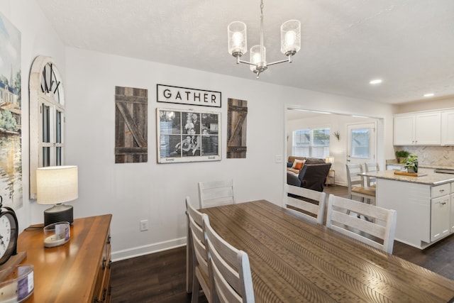 dining room with a textured ceiling, dark hardwood / wood-style floors, and an inviting chandelier