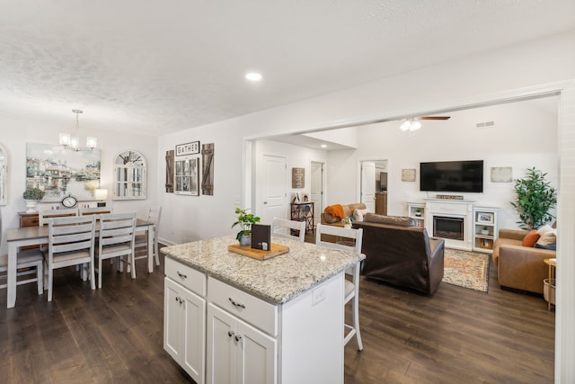 kitchen with dark wood-type flooring, a center island, decorative light fixtures, and white cabinets