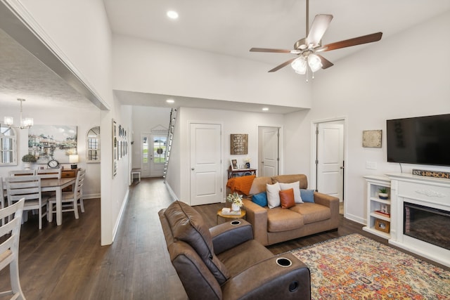 living room with a high ceiling, ceiling fan with notable chandelier, and dark hardwood / wood-style flooring