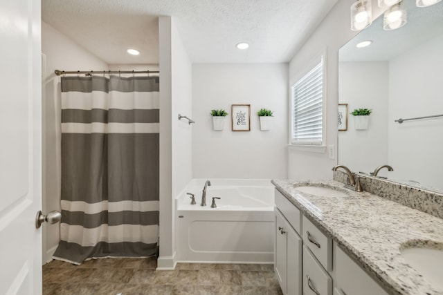 bathroom with vanity, a textured ceiling, and a bathing tub