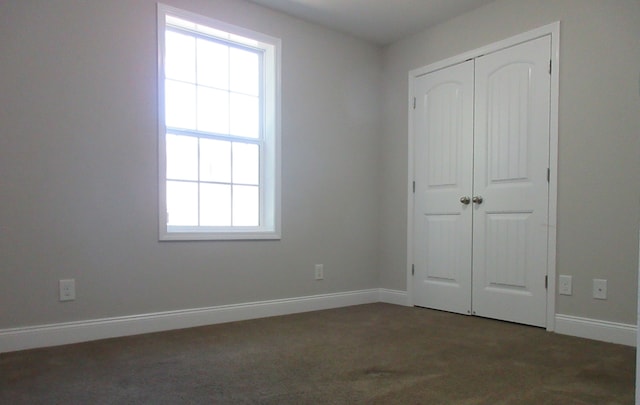 unfurnished bedroom with a closet and dark colored carpet