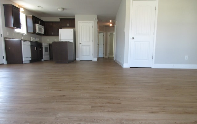 kitchen with sink, light hardwood / wood-style flooring, dark brown cabinets, and white appliances