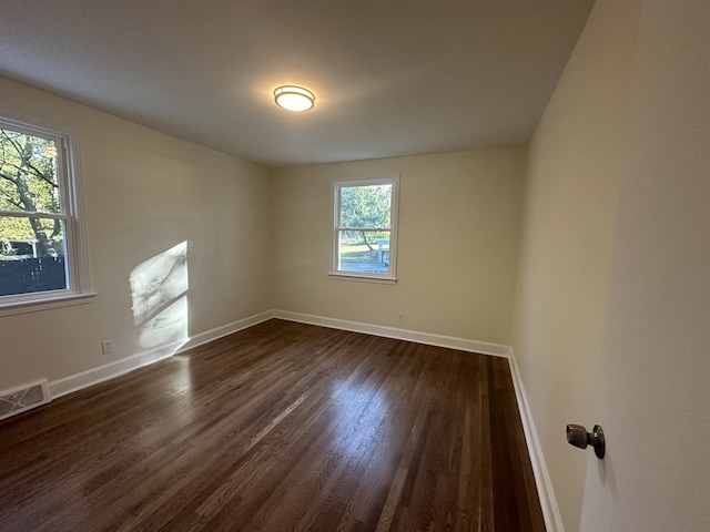 unfurnished room featuring dark hardwood / wood-style flooring and plenty of natural light