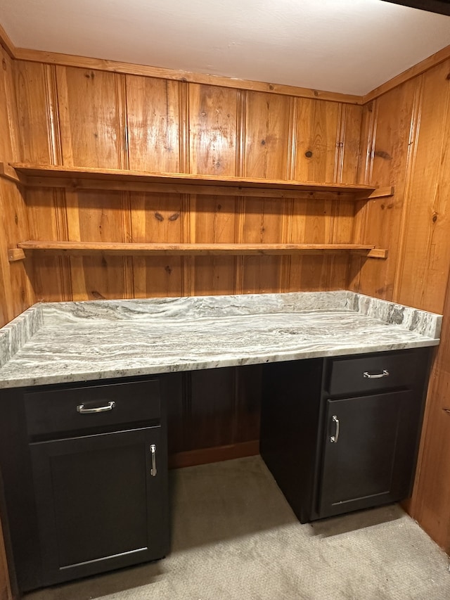 bar featuring light carpet, built in desk, and light stone counters